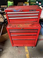 Two-piece red Craftsman tool chest stacked with six drawers and caster wheels in a storage environment