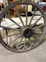 Full front view of the large wooden wagon wheel showing the spokes and wooden rim with metal outer band.