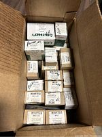 Photo showing multiple small cardboard boxes of screws neatly packed inside an open cardboard box, various type and size labels visible.