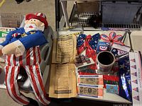 Overview photo of the large stuffed Uncle Sam figure seated showing full figure in patriotic clothing, surrounded by other Americana collectible items including matchbooks and currency replicas.
