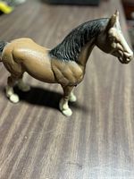 Side profile of cast iron Clydesdale horse figurine with black mane and brown body, showing details of muscular structure and paint finish.
