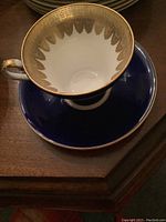 Photo of Aynsley teacup and saucer set showing gold patterned interior and cobalt blue exterior with gold trim