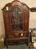 Front view of assembled cabinet with glass door and decorative carved wood overlay