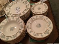 Stacks of side, salad and dinner plates with central floral motif and gold trim.