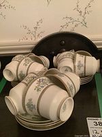 Grouped photo of several cups and saucers stacked on a dark surface, showing the floral and gold decorative pattern.