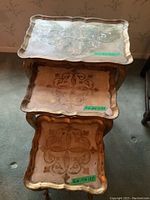 Photo showing all three nesting tables stacked top to bottom with visible wear and decorative tops.