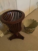 Photo showing entire wood spindle plant stand and metal painted pot side by side on carpeted floor.