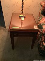 Front view of Furniture Guild side table with glass top and drawer closed, showing wood finish and tapered legs