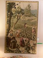 Full view of the tapestry hanging on a wall showing the pastoral vineyard scene with multiple figures harvesting grapes.