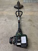 Full view of the Yardworks string trimmer laid on the floor showing the engine and cutting guard.