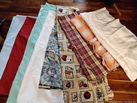 Overview of the nine folded tablecloths showing assorted colors and patterns including floral, plaid, and solid colors.