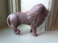 Side angle photo of the cast iron lion bank showing detailed mane, right side tail, and overall shape.