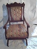 Front view of antique Eastlake rocking chair showing floral upholstered seat and backrest on wooden frame.