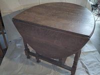 Top and side view showing round oak top with folded leaves and wood grain detail.