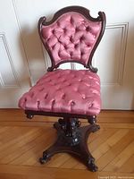 Front view of the Victorian walnut revolving chair showing pink tufted seat and backrest with carved wood frame.