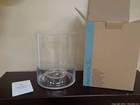 Photo of the clear glass pillar hurricane candle holder, instruction manual, and the original box.