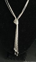 Front view of the necklace on a display bust highlighting the knot and the dangling ends of the multiple silver strands.