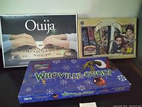 View of the three board games in their boxes: Ouija, A Series of Unfortunate Events, and Whoville-opoly.