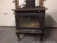 Front view of black steel wood stove showing glass door, curved legs, top surface and handle