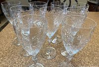 Ten tall water/wine crystal glasses with etched floral/leaf pattern and polished finish.