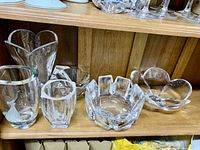Photo showing the 6 pieces on a wooden shelf including vases and bowls with etched designs and various shapes.