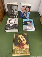 Photo of all five books showing their front covers on a green surface.