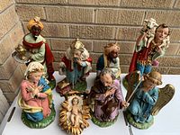 Full display of all seven hand-painted papier mache Nativity figurines on outdoor surface