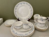 Full set with stacked dinner plates, cups on saucers, and tray with sugar bowl and creamer in front.