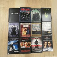 Photo showing 12 distinct DVDs including SE7EN, The Sopranos, The Matrix, Aliens, Shakespeare in Love, Saving Private Ryan, Platoon, Contact, Amores Perros, Raging Bull, and French Lieutenant's Woman.