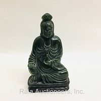 Front view of the dark green jade seated deity figure showing detailed facial features and robes.