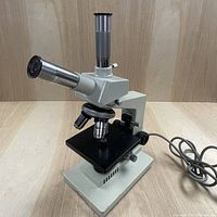 Full view of the microscope showing body, eyepiece, objectives, stage, and power cord.