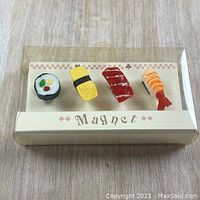 Photo of 4 different sushi food magnets in packaging on wooden surface
