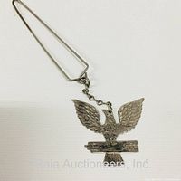 Full length image of a metal kid glove stretcher with an eagle figure, showing the triangular handle and chain attachment.