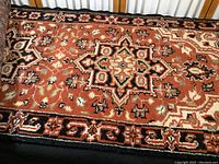 Close-up of the rust-toned carpet runner rug with intricate geometric and floral pattern including star-like central motifs and a decorative border.