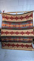 Full view of blanket hung against wall showing overall multicolor Southwest geometric pattern