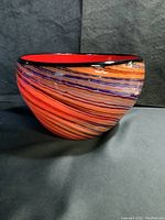 Front and side views of the swirl pattern glass bowl showing the multicolored swirl stripes, red interior, and black rim.