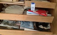 Drawer with various folded vintage handkerchiefs, fabric items, and boxed items.