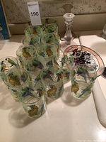 Cluster of parrot tumblers grouped on countertop with candlestick and plate behind