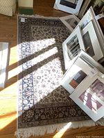 Overall view of rug laid on hardwood floor with framed artwork partially visible