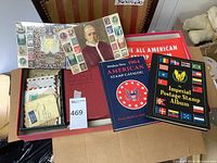 Four books and a box of loose stamps displayed in cardboard box