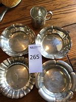 Top-down view of one sterling silver cup and four plates on wood surface