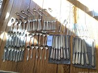 Full layout of flatware on wooden table showing knives, forks, spoons and ladles