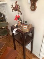 Small dark wooden table with Christmas and cat-themed decor on top including Santa with reindeer and several figurines.