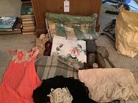 Overview of coral slip, folded linens, yarn skein, silver vanity items including shoehorns, and other cloth items.