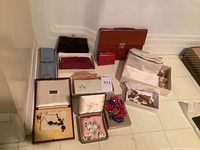 Overview of all items on floor including wallets, jewelry boxes, beaded necklace and wooden figurines