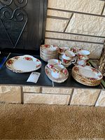 Overview of all dishes including dinner plate, stack of salad plates, teacups and saucers on hearth.