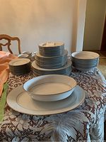 Full set on table showing stacks of plates, bowls, cups, serving pieces
