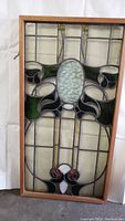 Full front view of framed stained glass panel leaning against white backdrop