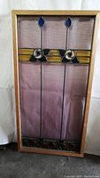 Full front view of framed stained glass panel showing overall design and wood frame.
