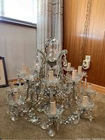 Front view of chandelier on floor showing two-tier design, glass arms and prisms